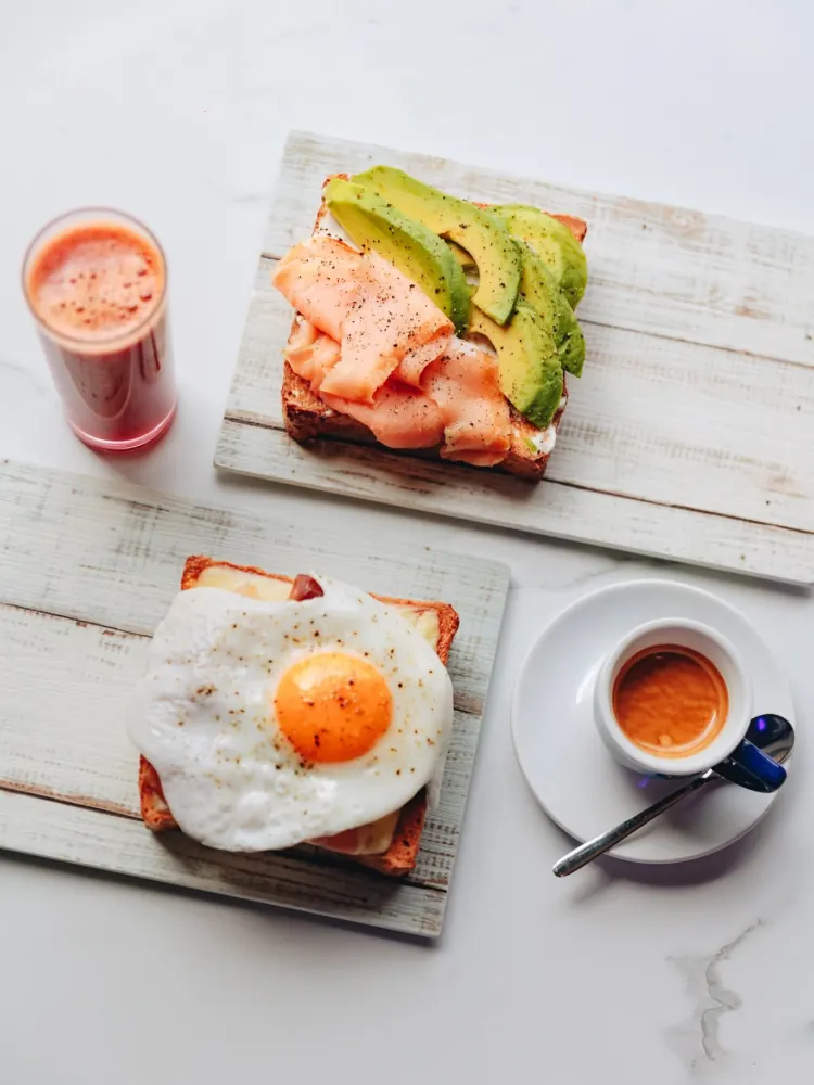 Toast con uovo all'occhio di bue, toast con salmone e avocado, centrifuga e caffè