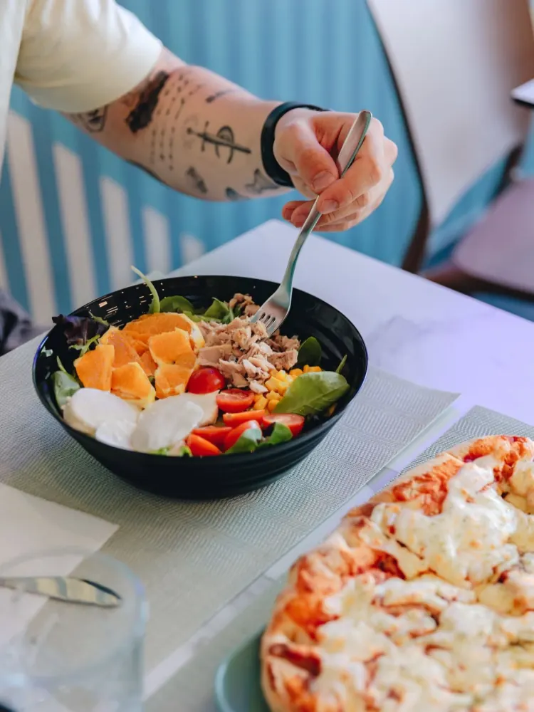 Insalatona in ciotola e pizza al tavolo della pasticceria